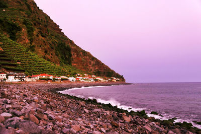 Scenic view of mountain by sea against sky during sunset