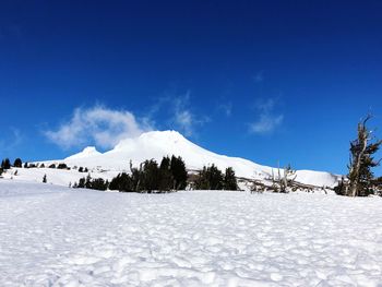 Scenic view of snow covered mountains against blue sky