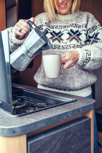Midsection of woman pouring coffee in cup