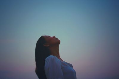 Low angle view of woman against clear blue sky