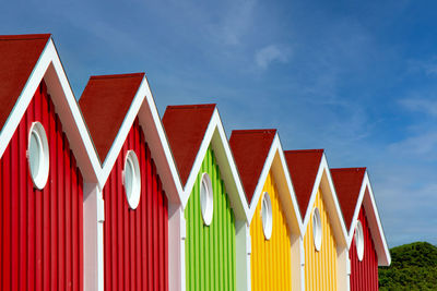 Low angle view of multi colored umbrellas on building against sky