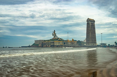 Building by sea against cloudy sky