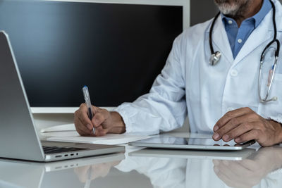 Midsection of doctor working at desk in office
