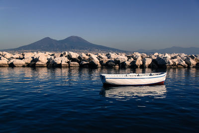 Boats in calm blue sea in front of mountains