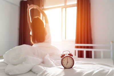 Close-up of alarm clock on bed at home