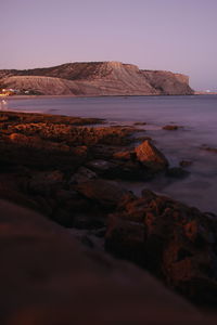 Surface level of rocks on shore against clear sky