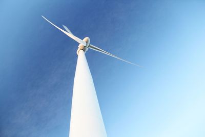 Low angle view of wind turbine against blue sky