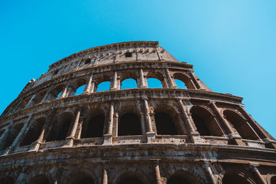 Low angle view of coliseum against clear blue sky