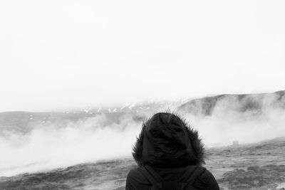 Rear view of boy looking at mountain against clear sky