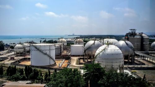 Aerial view of factory by sea against sky