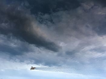 Low angle view of airplane flying against cloudy sky