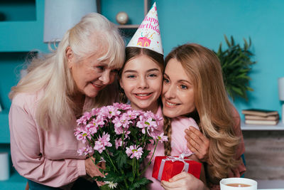 Smiling mother and grandmother embracing girl at home