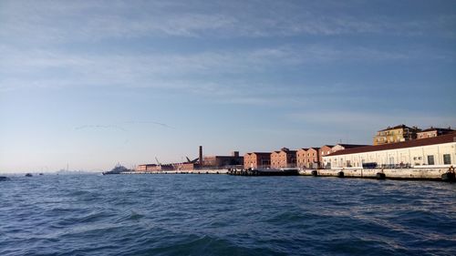 Sea by buildings in city against sky