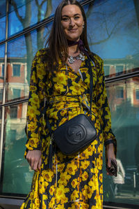 Young woman standing against yellow wall