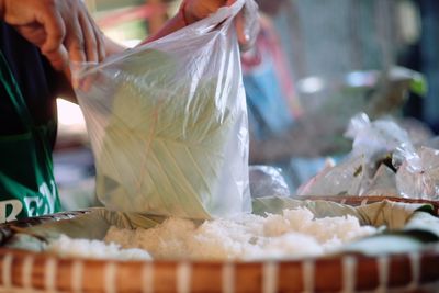 Cropped hand of person holding food in plastic bag at market