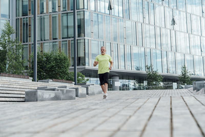 Mature man jogging on footpath in city