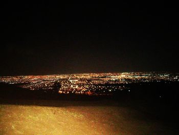 Illuminated cityscape against sky at night