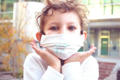 Portrait of girl wearing mask sitting outdoors