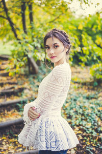 Beautiful young woman brunette with braids around head in white lace sleeve blouse in park. fall 