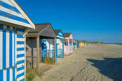 Colourful beach huts in a row overlook the beach at west wittering, on the south coast of england.