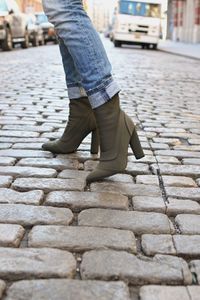 Low section of woman standing on cobblestone street