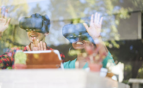 Smiling colleague looking through virtual reality simulators seen through window