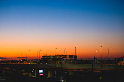 Illuminated city against sky at sunset