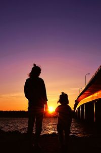 Silhouette couple standing at beach during sunset