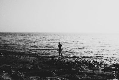 Man standing on beach against clear sky