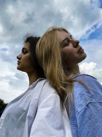 Midsection of woman looking at camera against sky