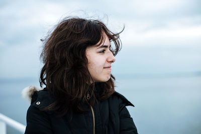 Pensive young girl looking to sea from boat. teenager girl at ferryboat. cold grey sea