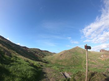 Scenic view of road amidst field against blue sky