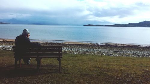 Man sitting on beach against sky