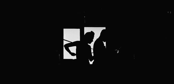 Silhouette people standing against window