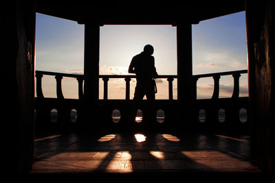 Silhouette man standing in balcony on sunny day