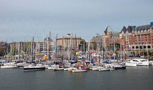 Sailboats moored in sea against buildings in city