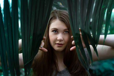 Portrait of beautiful young woman by leaves