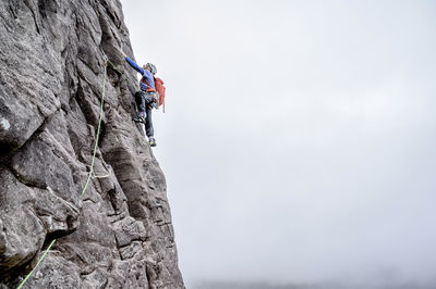 Man with backpack climbing rocky mountain