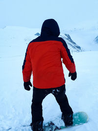 Rear view of boy standing in snow against sky