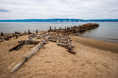 Wooden posts on beach against sky