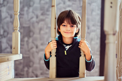 Portrait of boy sitting on railing