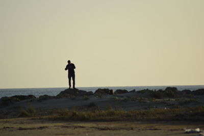 Man standing on beach against clear sky