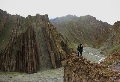 Rear view of man walking on mountain against sky