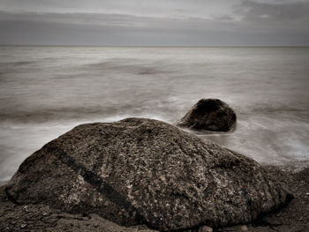 Rear view of rocks on beach against sky