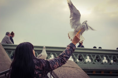 Low angle view of woman perching on hand against sky