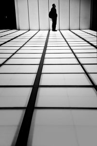 Rear view of man walking on tiled floor