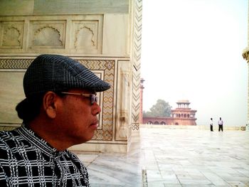 Portrait of young man looking away against building