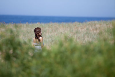 Woman standing on field against sea