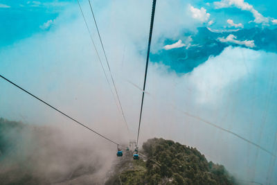 Low angle view of overhead cable car against sky