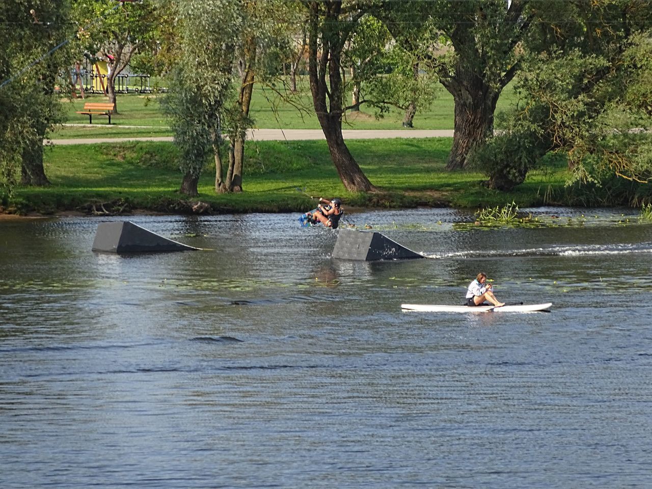 PEOPLE IN LAKE AGAINST TREES